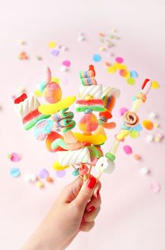 a person holding up a candy lollipop in front of confetti sprinkles