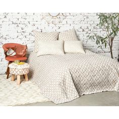 a bed sitting next to a red chair in front of a white brick wall with a clock on it