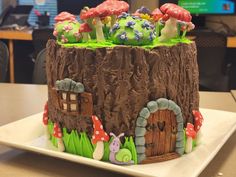 a cake made to look like a tree stump with mushrooms and houses in it on a plate