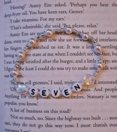 a bracelet that says seven on it with pearls and crystal beads in front of an open book