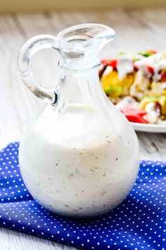 a glass bottle filled with dressing next to a plate of salad