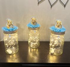 three mason jars with teddy bears in them are sitting on a table next to each other