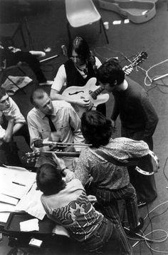 a group of people standing around each other with guitars