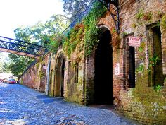 an old brick building with vines growing on it's side and a bridge over the street