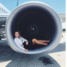 a woman is sitting in the middle of an airplane's engine tube as she poses for a photo