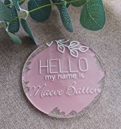 a pink glass plaque with the words hello my name is maee baton on it