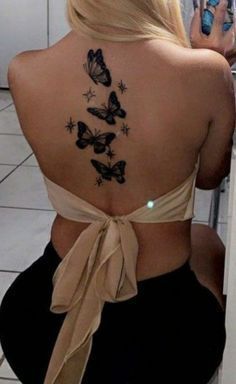 the back of a woman's neck with butterflies on her upper and lower back