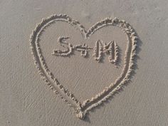 a heart drawn in sand with the word san written on it's side and an i love you sign at the bottom