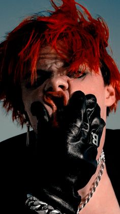 a man with red hair and black gloves covering his face