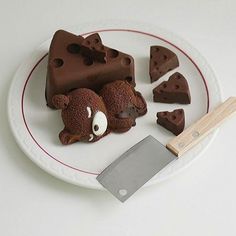 a white plate topped with chocolate pieces and a bear cut in half next to a knife