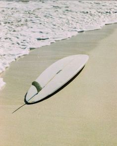 a surfboard is laying on the sand at the beach