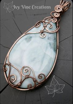 an image of a pendant made out of copper wire and glass with swirls on it