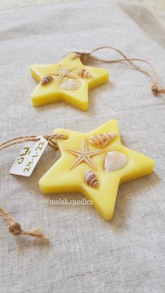 two yellow starfish shaped candles with seashells on them