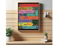 a colorful poster hanging on the wall above a wooden shelf next to a potted plant