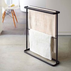 a towel rack with two towels hanging from it's sides in front of a chair