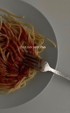 a plate with spaghetti and tomato sauce on it next to a fork that says italian mood