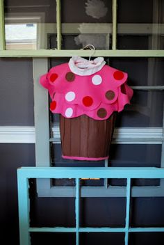 a cupcake costume is hanging on a window sill in front of a shelf