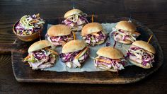 several sandwiches with toothpicks in them on a wooden tray