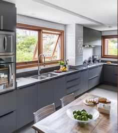 a modern kitchen with stainless steel appliances and wooden table in the center, surrounded by windows