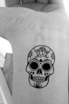 a woman's arm with a tattoo on it that has a skull and flowers