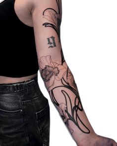 a woman's arm with flowers on it and the letter k tattooed in black ink