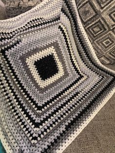 there is a crocheted blanket on the couch with it's square in the center