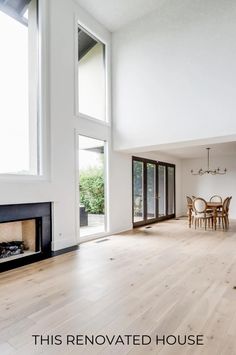 an empty living room with white walls and wood flooring that has a fireplace in it