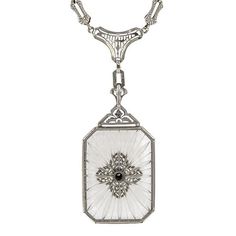 Centering a Round Brilliant cut diamond weighing approx. 0.03ct., on a rectangular sunburst carved rock crystal measuring approx. 30 x 22mm., in an embossed frame, topped and suspended from filigree components, finished by an embossed link chain, fashioned in 14k white gold. Length 16 inches. Luxury Art Deco Filigree Necklace, Exquisite Engraved White Jewelry, Exquisite White Engraved Jewelry, Antique Diamond Intaglio Jewelry, White Gold Rectangular Necklace With 17 Jewels, Elegant White Rectangular Pendant Jewelry, Elegant White Rectangular Jewelry, Vintage Rectangular Intaglio Jewelry, Antique Diamond White Pendant Jewelry