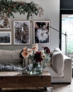 a living room with pictures on the wall and flowers in a vase sitting on a coffee table