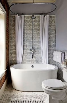 a white bath tub sitting next to a toilet in a bathroom under a skylight