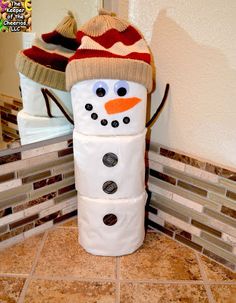 a snowman made out of toilet paper sitting on top of a tile floor next to a mirror