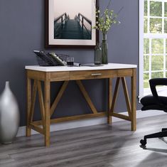 a desk with a chair and vase on it in front of a painting hanging on the wall