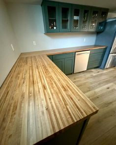 an empty kitchen with green cabinets and wood counter tops in the middle of the room