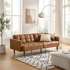 a brown leather couch sitting on top of a wooden floor next to a white rug