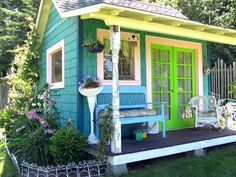 a small blue and green house sitting in the grass