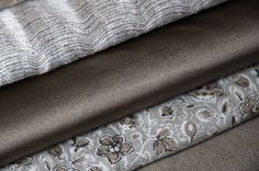 four different fabrics stacked on top of each other in various colors and patterns, including brown