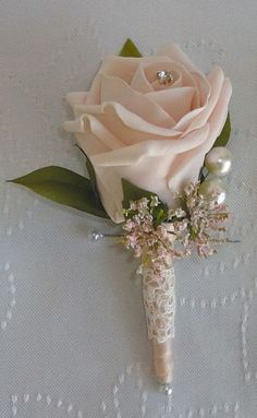 a boutonniere with flowers and pearls on the bottom is laying on a white tablecloth