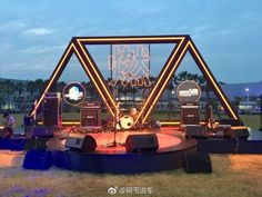 an outdoor stage set up with lights and music equipment on the ground in front of it