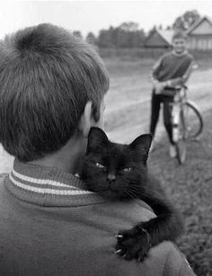 a man holding a black cat in his arms with an image of a boy on the back