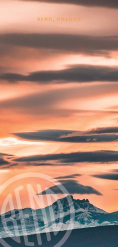 an orange and pink sky with some clouds in the foreground, mountains in the background