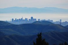 the city is in the distance with mountains and trees