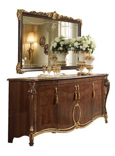 an ornately decorated sideboard with flowers and vases on it in front of a large window