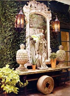 a large mirror sitting on top of a wooden table next to potted plants and vases