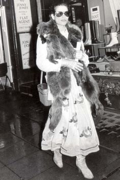 an old photo of a woman holding a teddy bear in her arms and wearing sunglasses