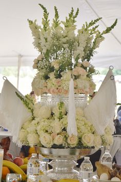 an arrangement of flowers and fruit on a table in front of a tented area