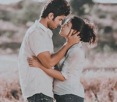 a man and woman standing next to each other in front of some tall brown grass