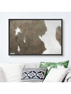 a cow print hanging on the wall above a couch