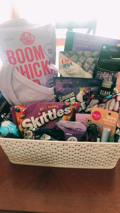 a white basket filled with lots of different types of snacks and candys on top of a wooden table