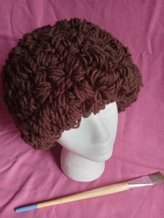 a crocheted brown hat sitting on top of a white mannequin head