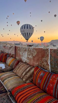 a couch with many pillows on it and hot air balloons in the sky